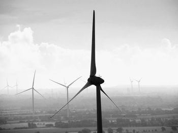 Wind turbines on field against sky