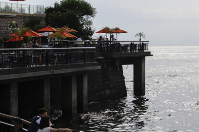 People on pier over sea against sky