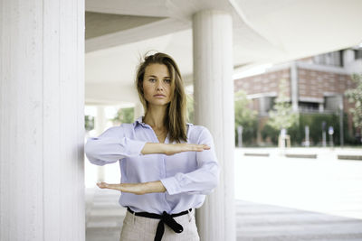 Portrait of young woman standing against white wall
