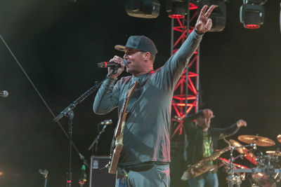 Midsection of man standing at music concert at night