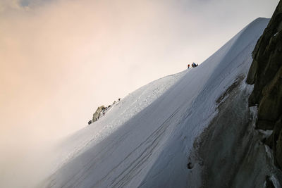 People on snowcapped mountain against sky