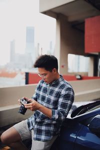 Man holding smart phone while standing in car