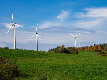 Wind turbines on field against sky