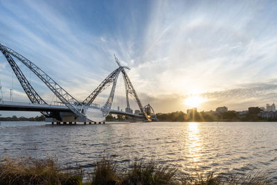 Bridge over river against sky during sunset