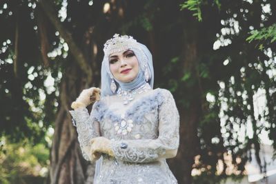 Portrait of woman standing by tree in forest