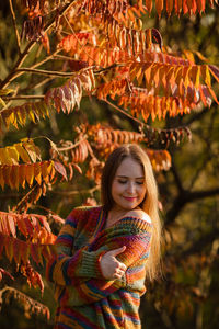 Portrait of young woman standing amidst plants