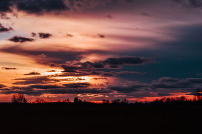 Silhouette landscape against dramatic sky during sunset