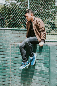 Full length of man sitting against wall