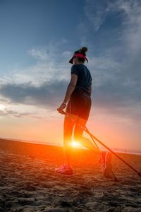 Woman standing on beach against sky during sunset