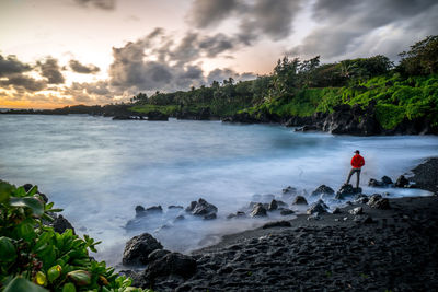 Rear view of man looking at sea during sunset