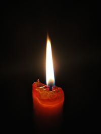 Close-up of burning candle against black background