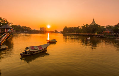 Boat in river against sky during sunset