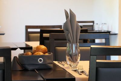 Close-up of fresh buns by napkin in glass on table at restaurant