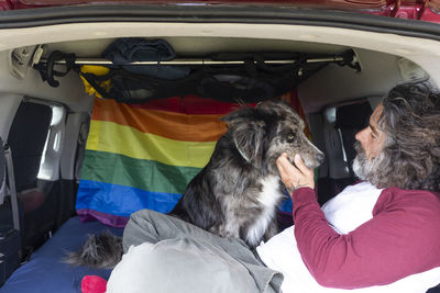 Homosexual man sitting with his black pet dog on the bed relaxing and enjoying the sunny day. person