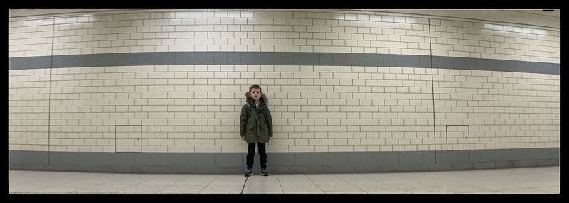 Portrait of young woman standing against tiled wall