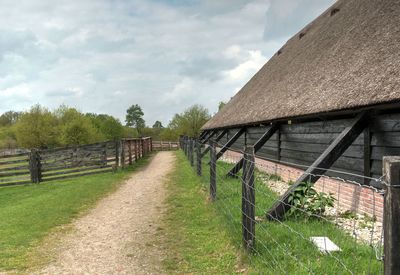 Walkway amidst houses and trees on field against sky