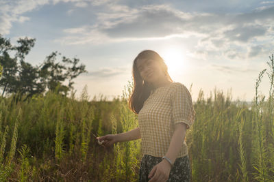 Woman standing on field against sky during sunset