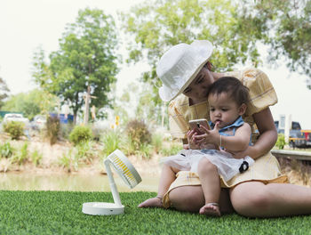 Young woman using mobile phone while sitting on field