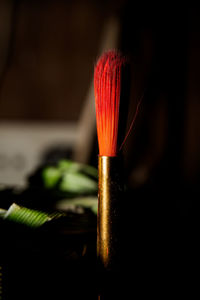 Close-up of red paint on table against black background