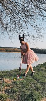 Woman stands in front of the lake and plays golf with the eggs