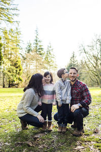 Affectionate family of four posing outdoors.