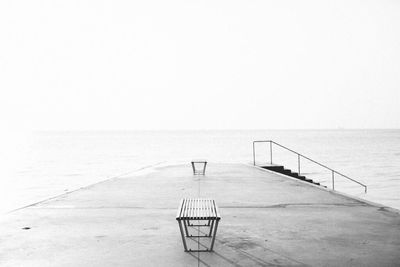 Empty pier on sea against clear sky