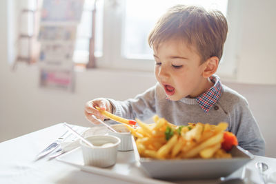 Boy eating food on table