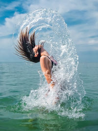 Side view of teenage girls splashing water in sea