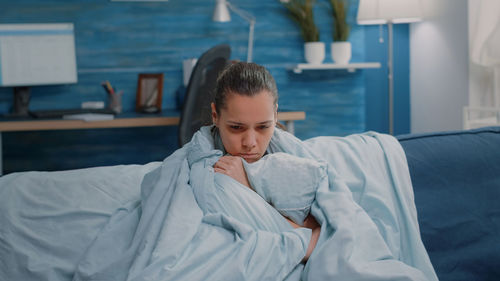 Portrait of boy sitting on bed at home