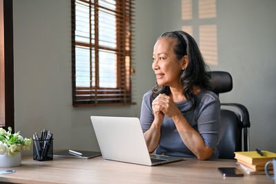 Young woman using laptop while sitting on table