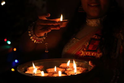 Midsection of illuminated man holding burning candles