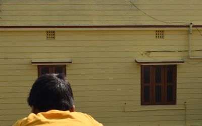 Rear view of man against yellow building