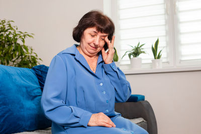 Mid adult man sitting against blue wall