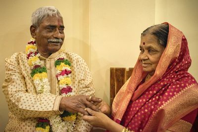 Senior woman inserting ring in senior man finger during anniversary celebration at home
