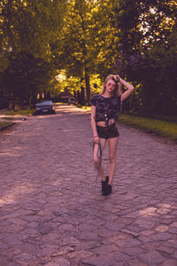 Beautiful young woman standing on footpath at park