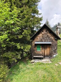 House and trees by plants against sky