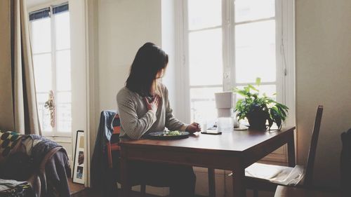Woman sitting on table at home