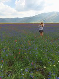 Rear view of woman standing in field against sky