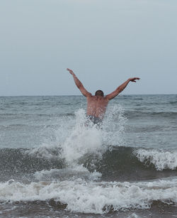 Man splashing water in sea against clear sky