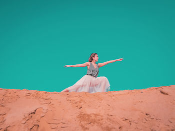 Woman with arms outstretched on sand