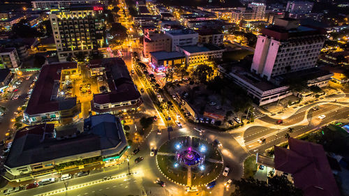 High angle view of illuminated street amidst buildings at night