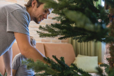 Side view of young man sitting on tree