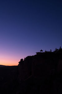 Silhouette rock formations against clear blue sky during sunset