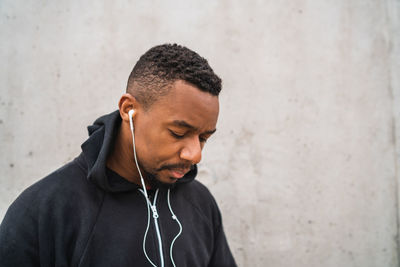Young man looking at camera while standing against wall