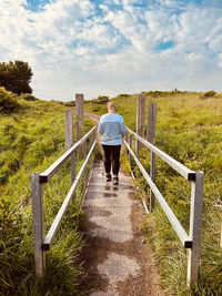 Rear view of woman walking across a bridge