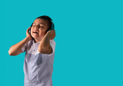 Happy boy standing against blue background