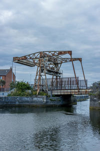 Ferris wheel by river against sky