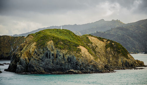 Scenic view of rocks by sea against sky