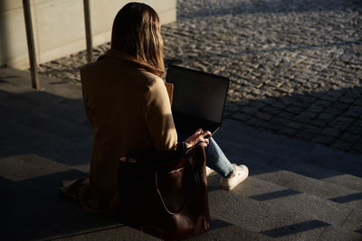 Woman working online, using laptop at city street. remote work and freelance