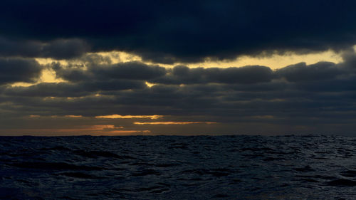 Scenic view of sea against dramatic sky during sunset